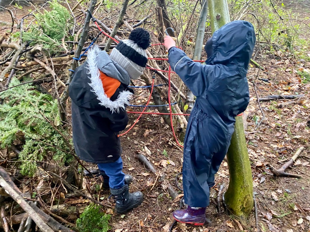 Working cooperatively to build a den in the woods using grappling hooks